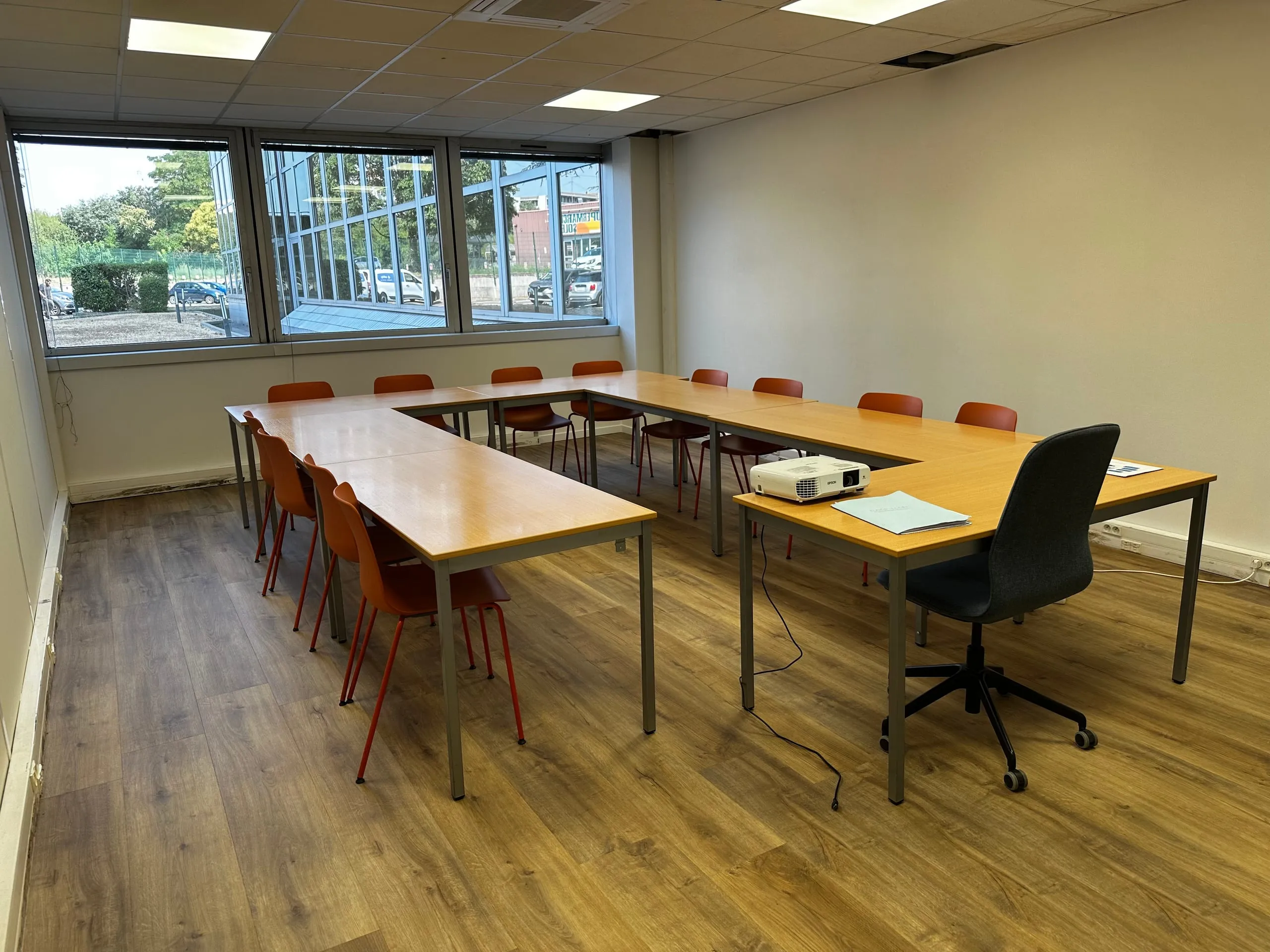 Salle de formation du CFA Paedagogia équipée d'un projecteur et de tables en U